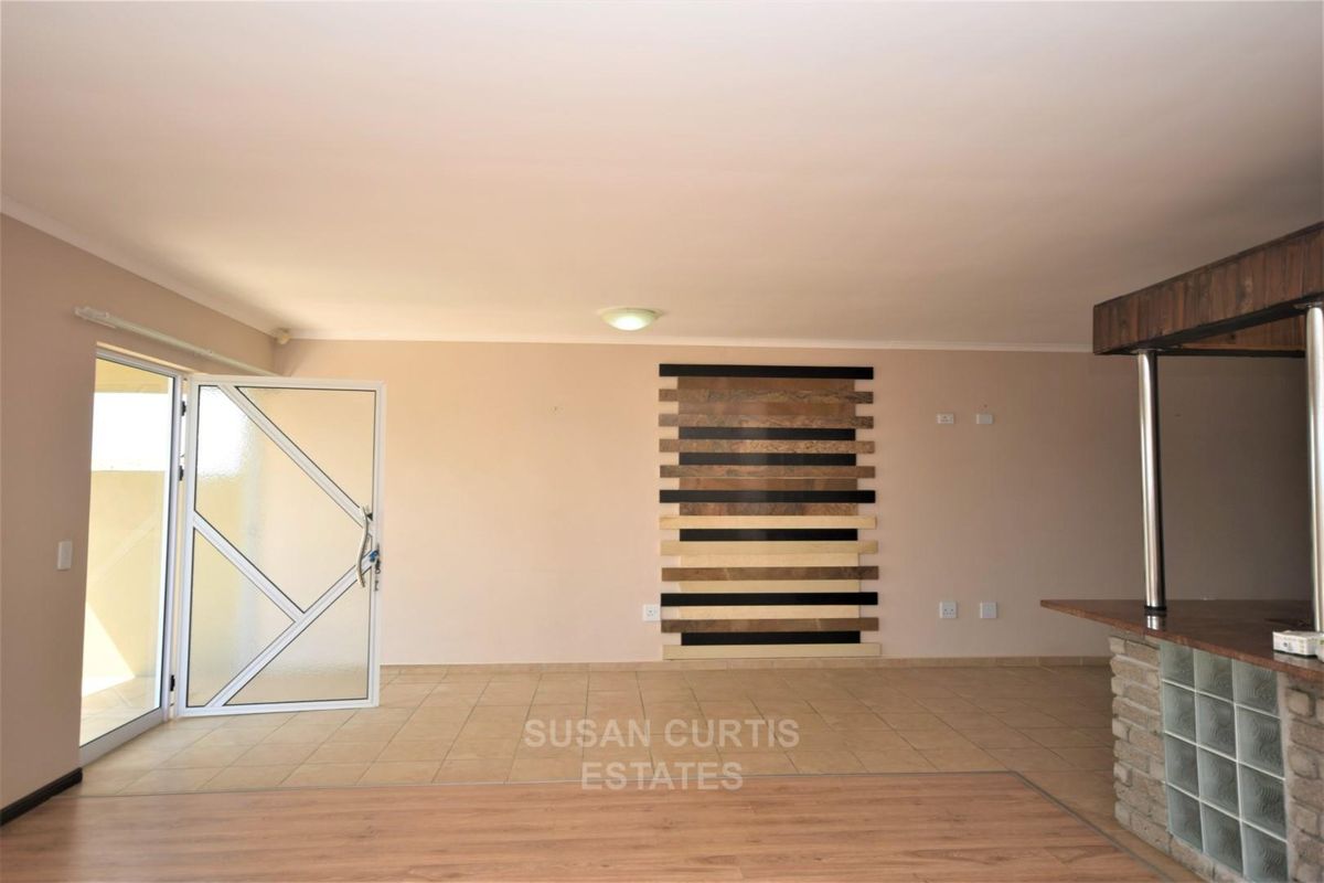 An open-plan living area featuring tiled and laminate flooring, a breakfast bar with glass block accents, and a decorative wall feature.