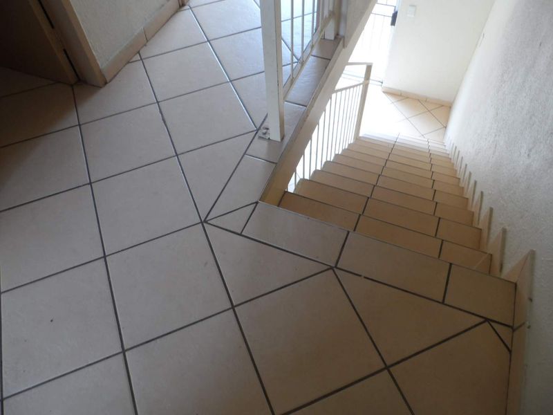 A functional staircase featuring ceramic floor tiles and a simple metal balustrade, providing access between levels in the apartment.