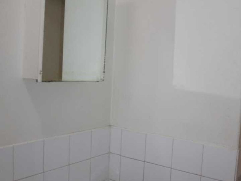 A functional bathroom space featuring a wall-mounted basin with chrome faucet, tiled splashback, and a medicine cabinet.