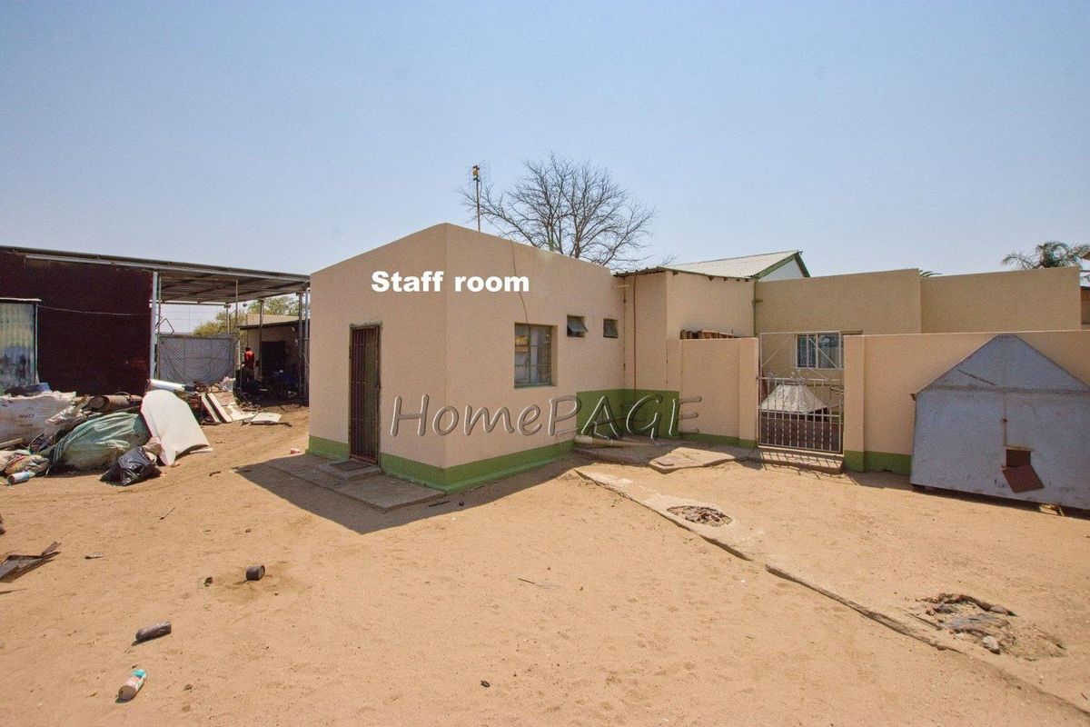 Exterior view of a detached staff room building featuring masonry construction, metal security door, and basic window fixtures within an industrial yard setting.