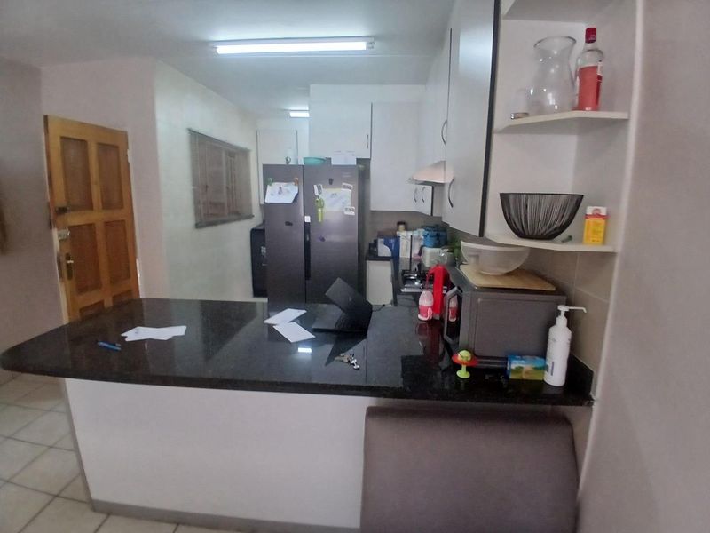 A functional kitchen featuring a granite breakfast bar, built-in cabinetry, and tiled flooring, providing a practical workspace for daily meal preparation.