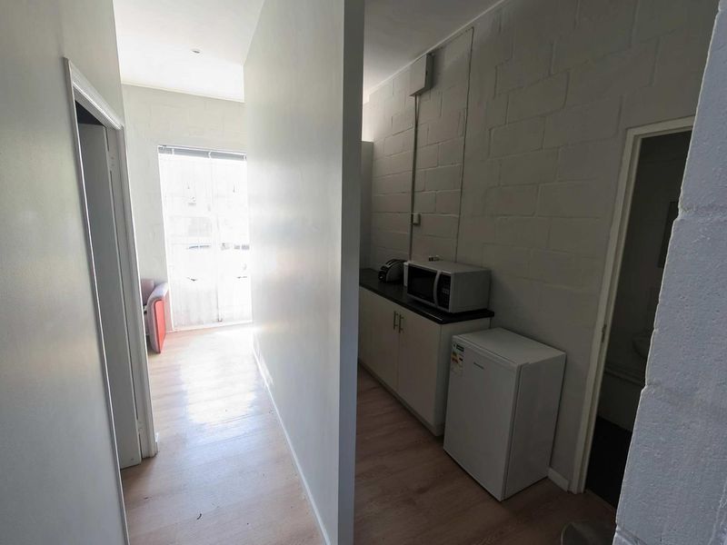 A functional scullery or kitchenette area featuring built-in cabinetry, laminate flooring, and exposed brick walls, providing practical utility space.