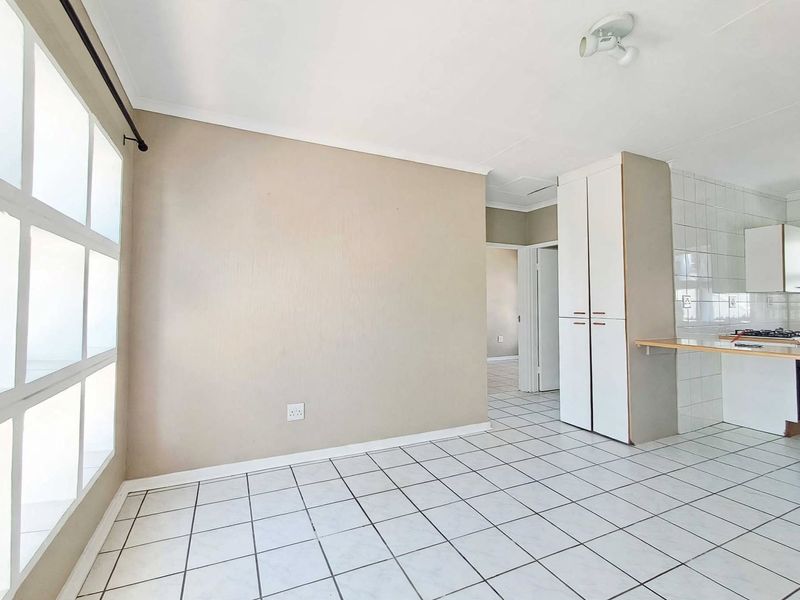 An open-plan living and kitchen area featuring tiled flooring, built-in storage cupboards, and a functional kitchen workspace with a hob.