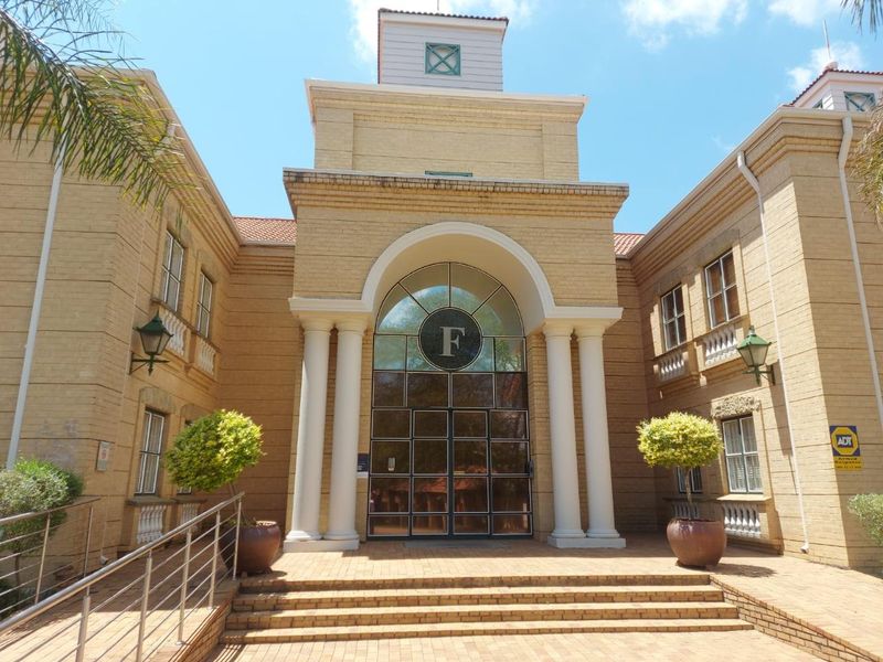 Front elevation of a professional office building featuring a prominent arched entrance, brick facade, and classic architectural columns.