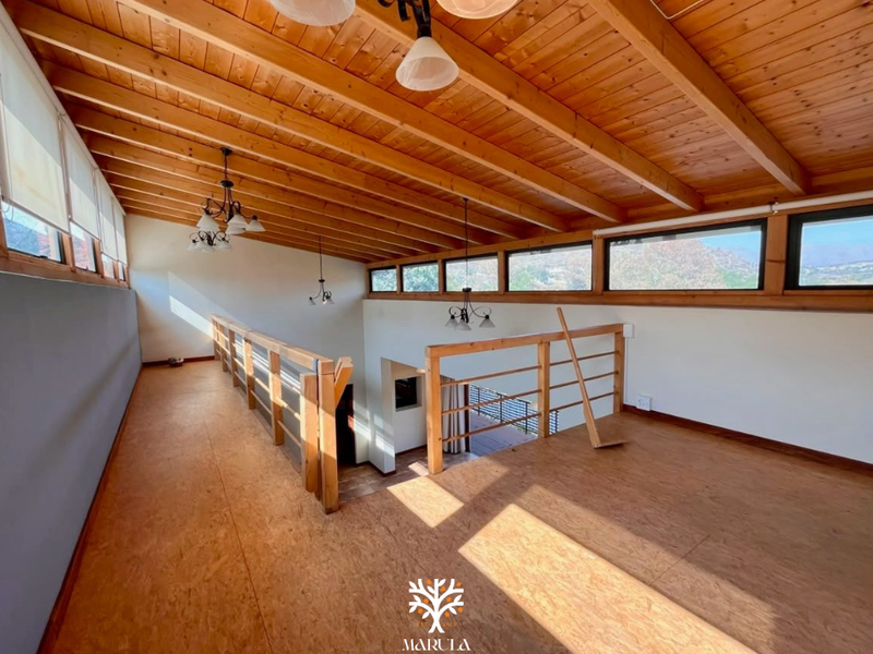 Spacious mezzanine living area featuring exposed timber beam ceilings, clerestory windows, and timber flooring, overlooking the lower level.