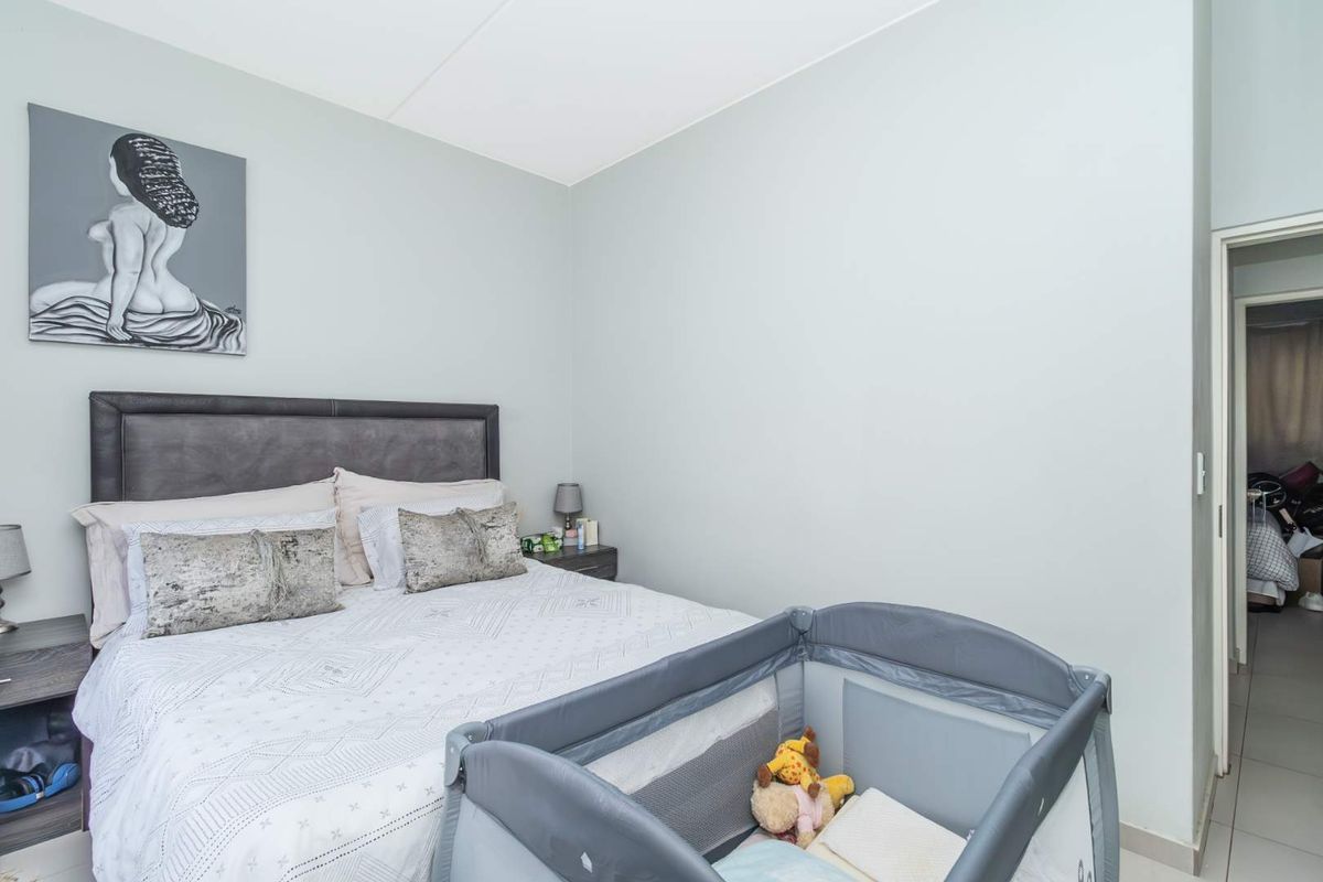 A standard bedroom featuring neutral wall finishes and tiled flooring, with a doorway leading to an adjacent room.