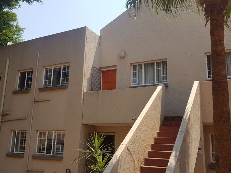 Exterior view of a multi-story apartment building featuring a concrete staircase, balcony access, and standard window placements.