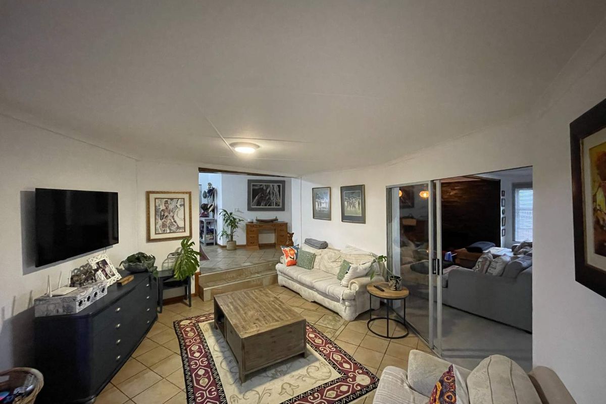 A living room featuring ceramic tile flooring, coved ceilings, and a sliding glass door providing access to an adjacent space.