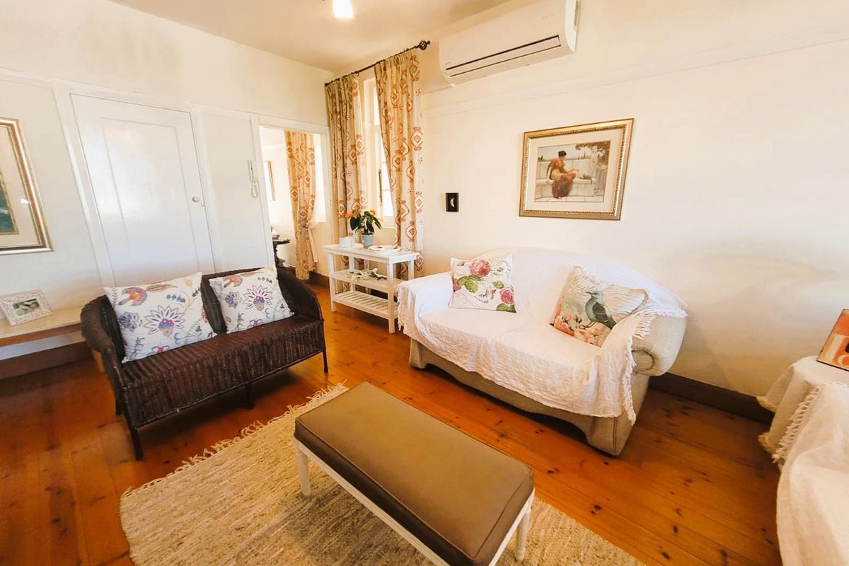A cozy living room featuring polished timber flooring, a wall-mounted air conditioning unit, and classic architectural details.