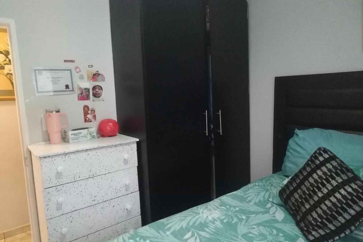 A bedroom featuring a built-in dark wardrobe and tiled flooring.