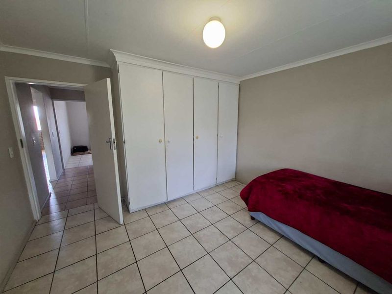 A bedroom featuring tiled flooring and built-in cupboards, providing functional storage space within the apartment.