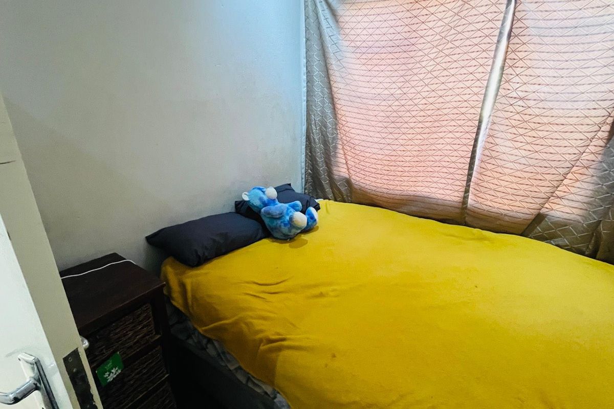 A compact bedroom featuring a window with curtains and neutral wall finishes.