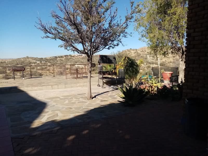 An outdoor patio area featuring stone paving, a brick wall, and metal railings, offering an open space with views of the surrounding landscape.