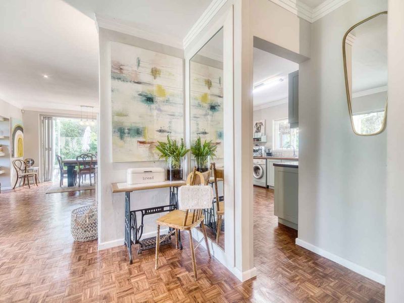 A bright hallway featuring classic parquet flooring and a large built-in mirror, providing a seamless transition between the living area and the kitchen.