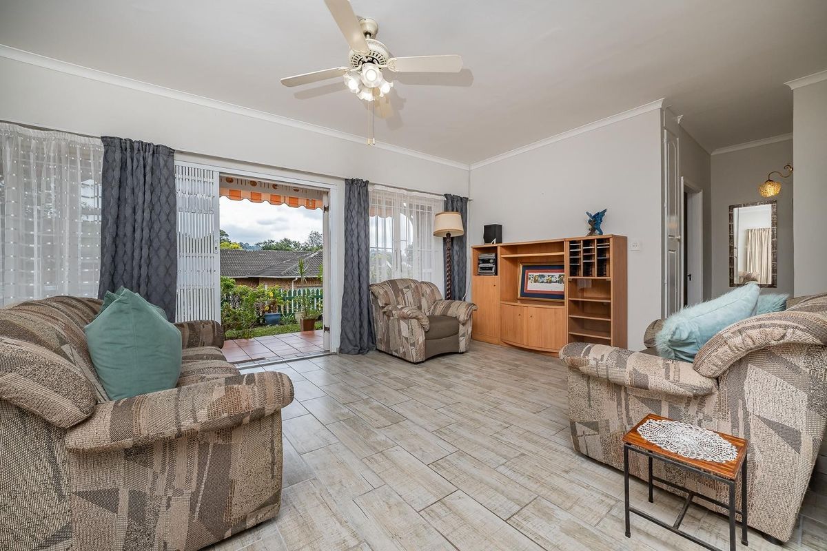 A spacious living room featuring tiled flooring, a ceiling fan, and direct access to an outdoor patio area through sliding glass doors.