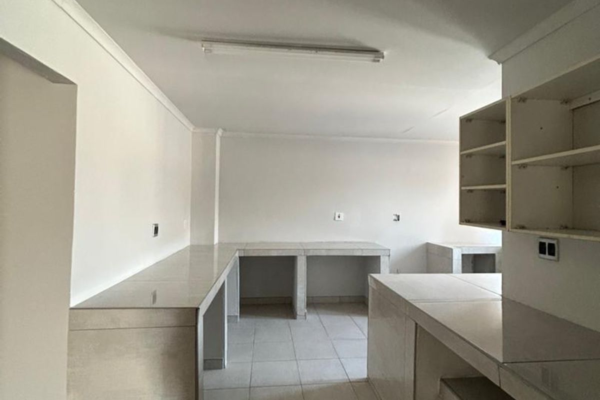 An empty, functional kitchen space featuring tiled countertops, built-in masonry cabinetry, and open shelving, ready for customization.