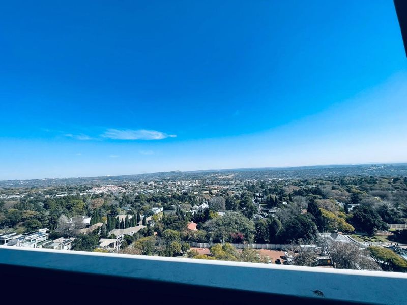 Elevated panoramic view overlooking the surrounding suburban landscape and greenery from an apartment balcony.