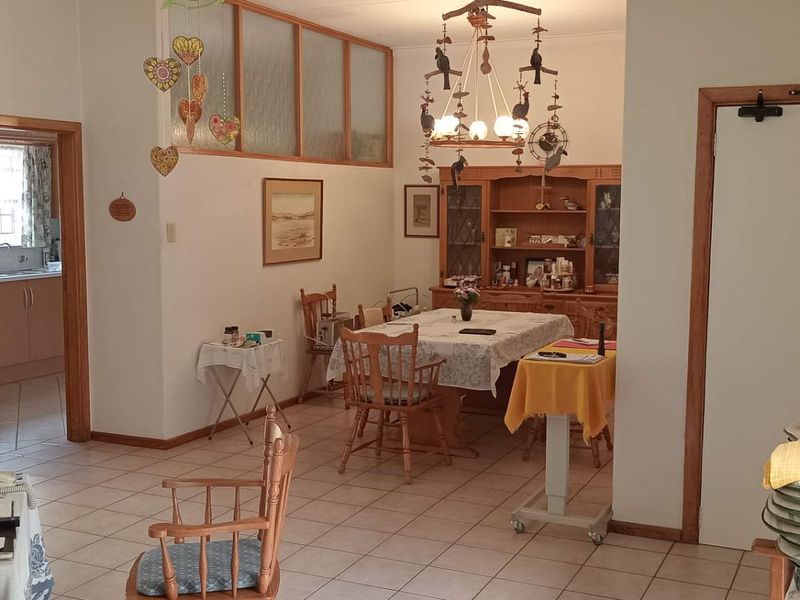A dining area featuring tiled flooring, timber door frames, and built-in cabinetry, with an open layout connecting to adjacent rooms.