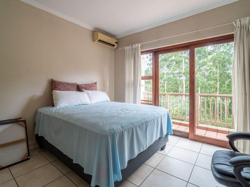 Bedroom featuring tiled flooring, wall-mounted air conditioning, and sliding glass doors opening onto a private balcony with scenic views.