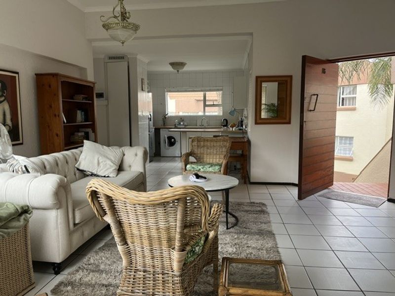 Open-plan living area featuring tiled floors, a functional kitchen with built-in cabinetry, and direct access to the exterior entrance.