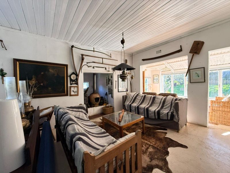 Rustic living room featuring a wood-burning fireplace, tongue and groove ceiling, and direct access to an adjoining sunroom area.