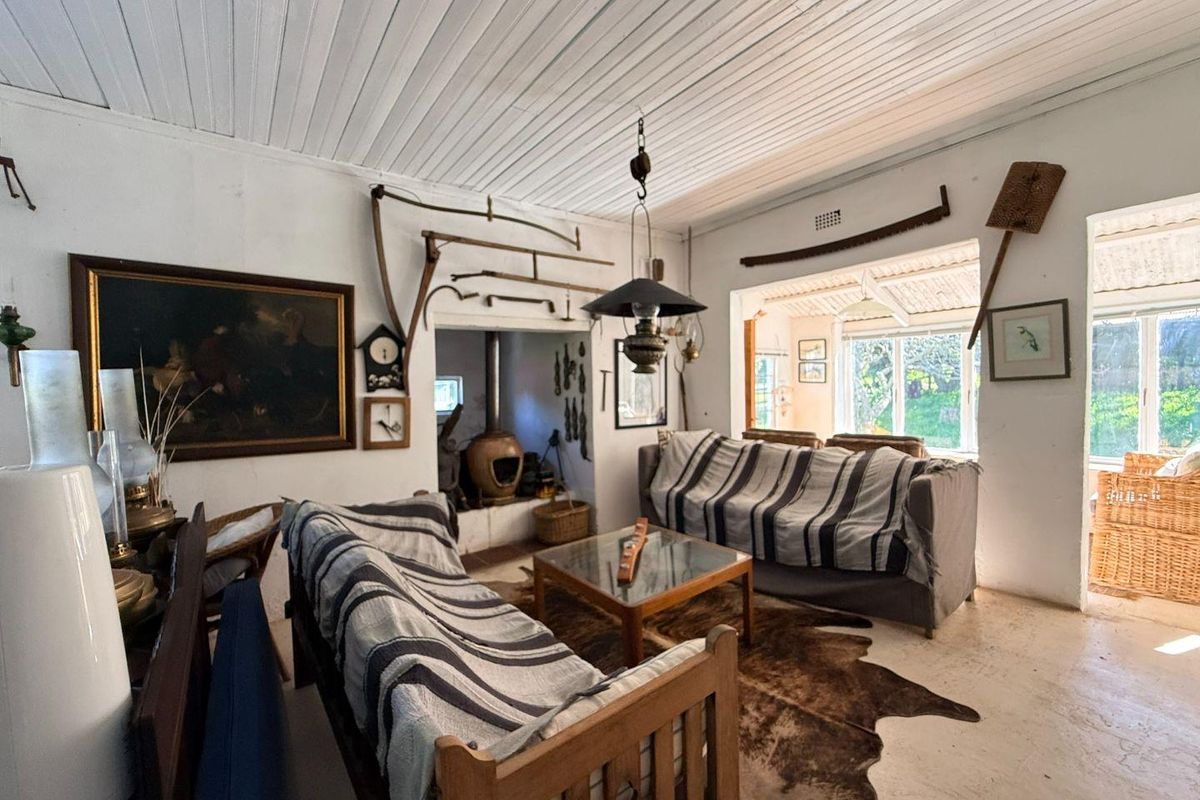 Rustic living room featuring a wood-burning fireplace, tongue and groove ceiling, and direct access to an adjoining sunroom area.