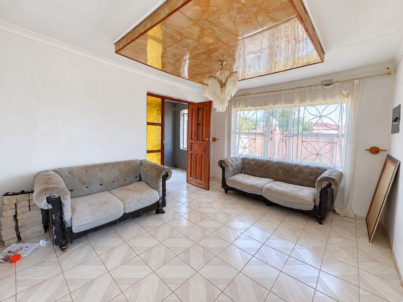 Living room featuring ceramic floor tiles, a decorative ceiling panel, and security bars on the windows.