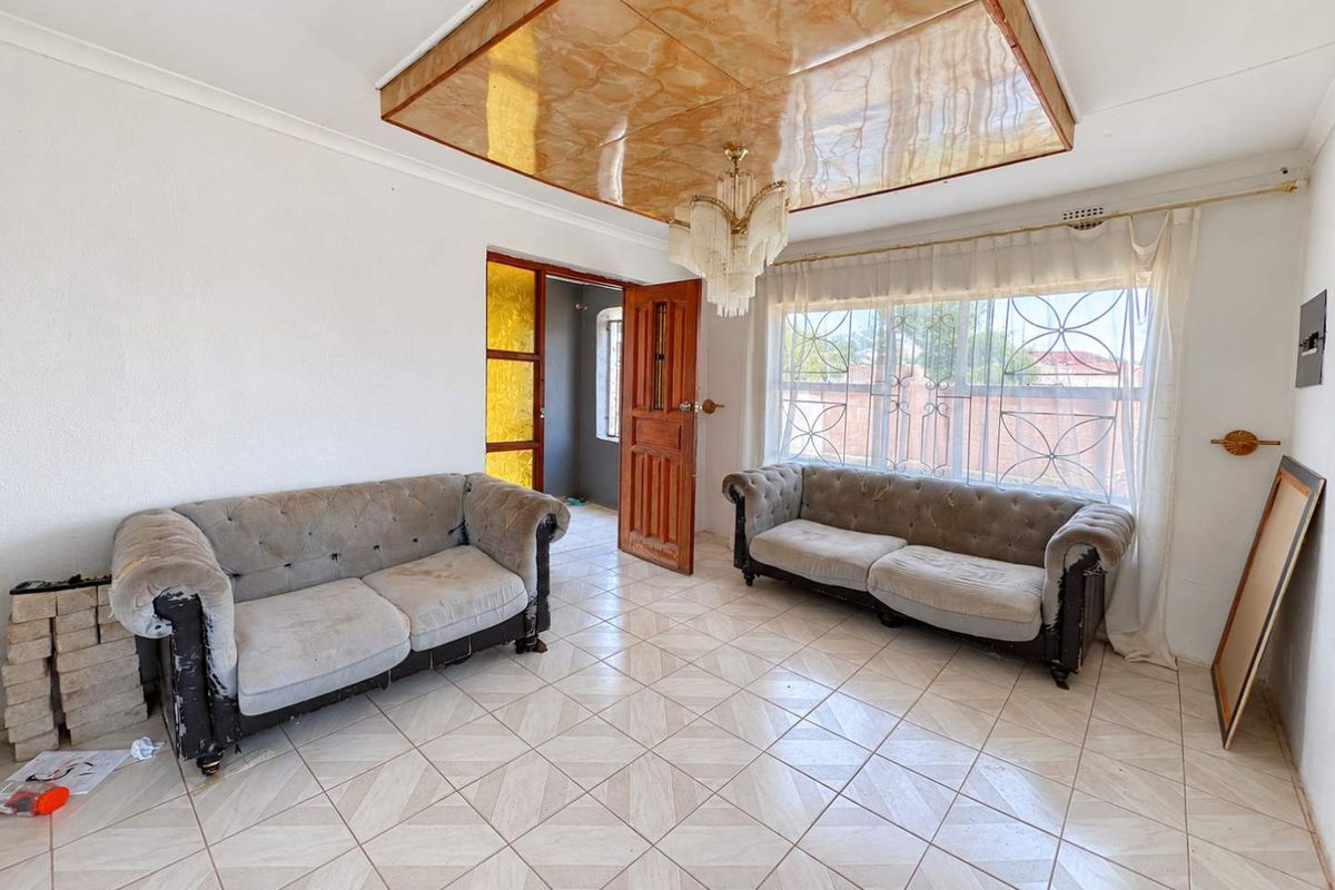 Living room featuring ceramic floor tiles, a decorative ceiling panel, and security bars on the windows.