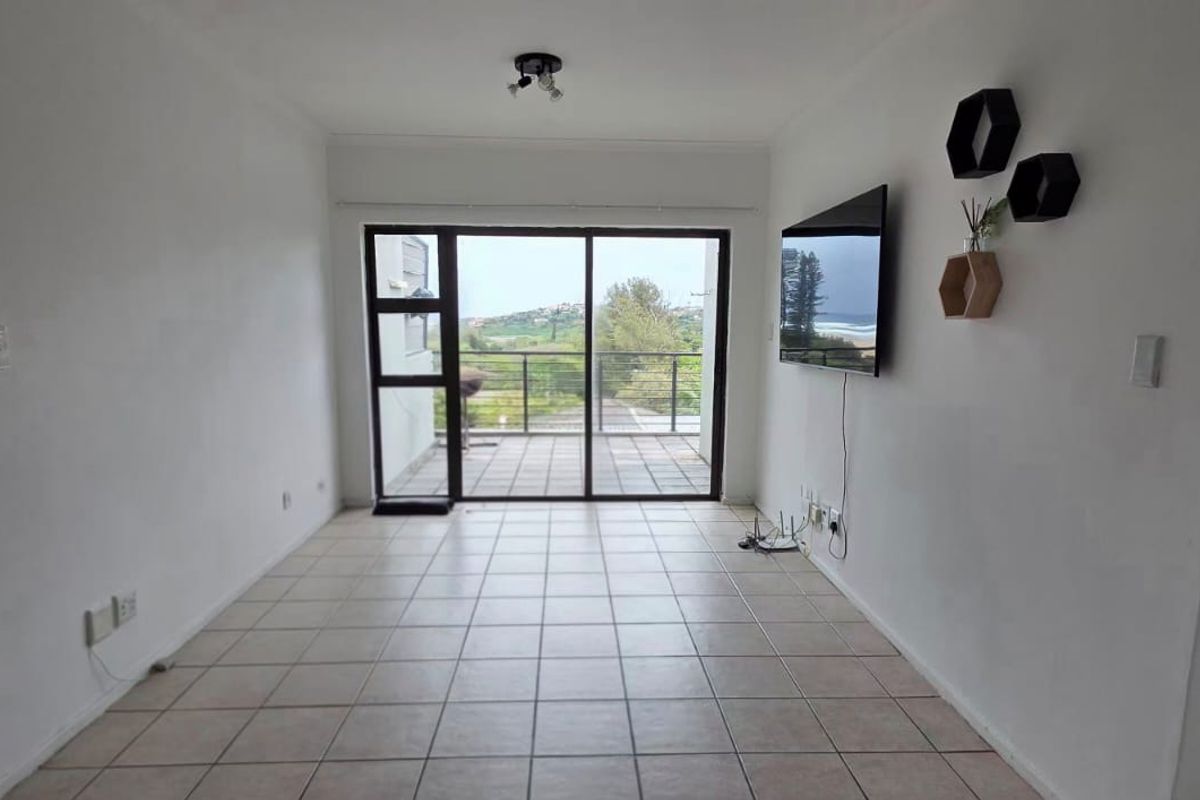Bright and open living area featuring neutral tiled flooring and large sliding glass doors that provide direct access to a private balcony.