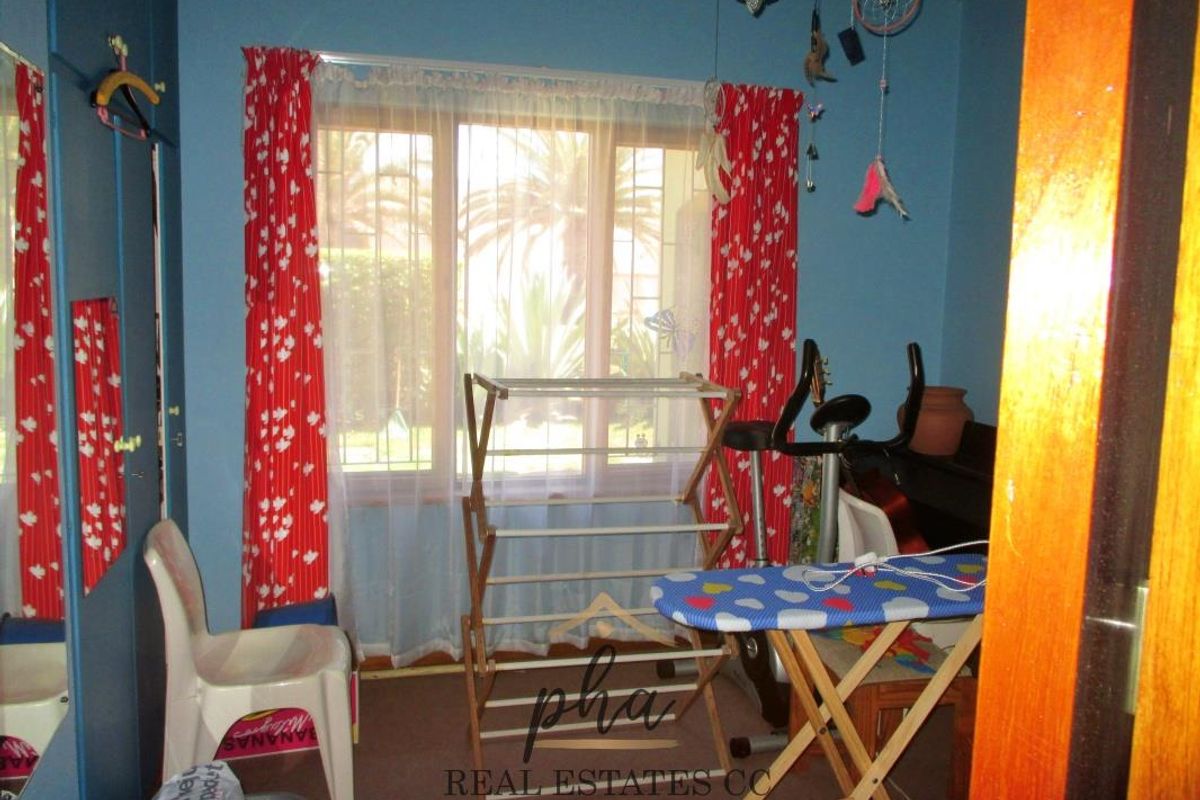 A bedroom featuring blue walls and a window with security bars, currently utilized as a multi-purpose utility and exercise space.