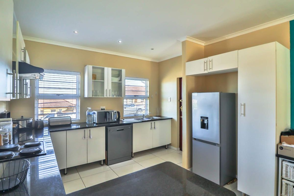 Modern kitchen featuring white cabinetry, dark granite countertops, tiled flooring, and integrated appliance space, offering a clean and functional culinary environment.