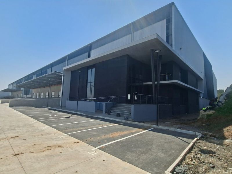 Modern industrial warehouse facility featuring a large concrete loading apron, dedicated parking bays, and contemporary steel and masonry facade construction.
