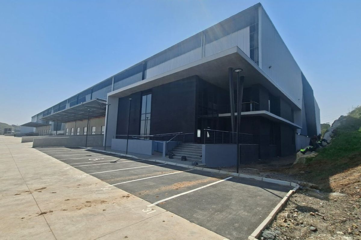 Modern industrial warehouse facility featuring a large concrete loading apron, dedicated parking bays, and contemporary steel and masonry facade construction.