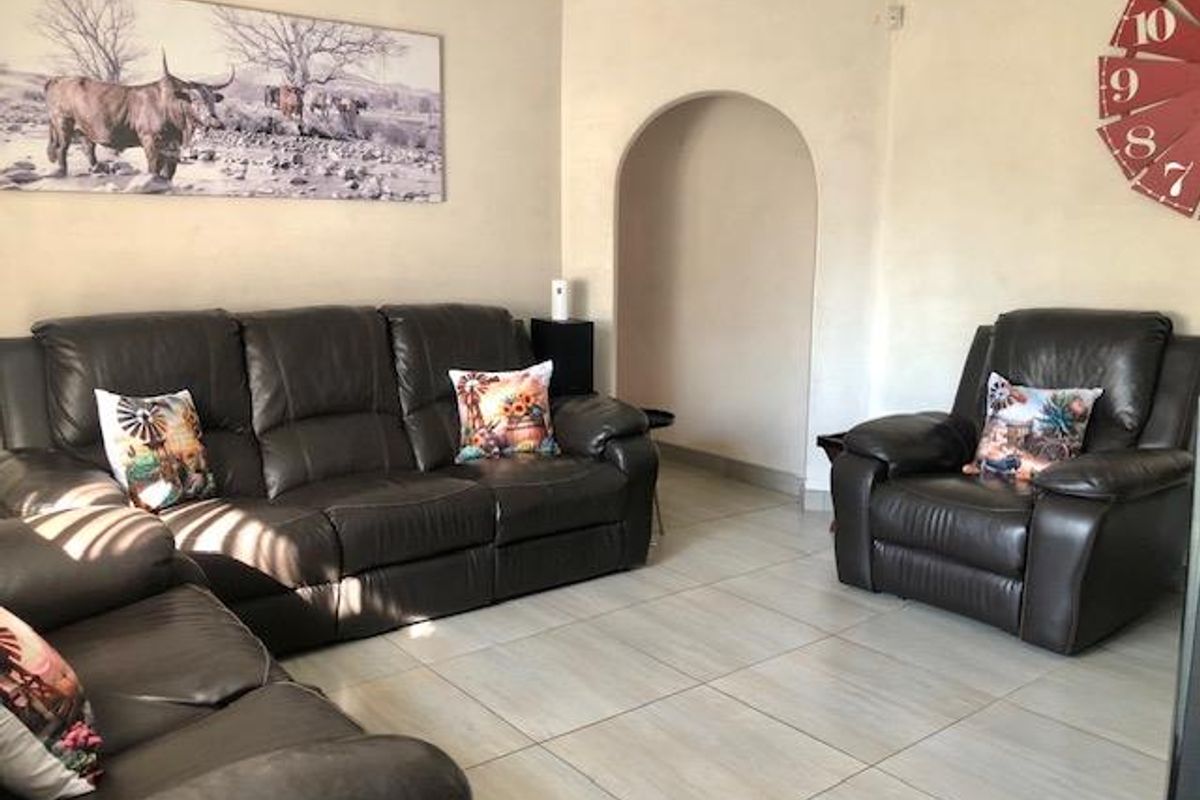 A living room featuring neutral tiled flooring and a distinctive arched wall alcove, providing a functional and open living space.