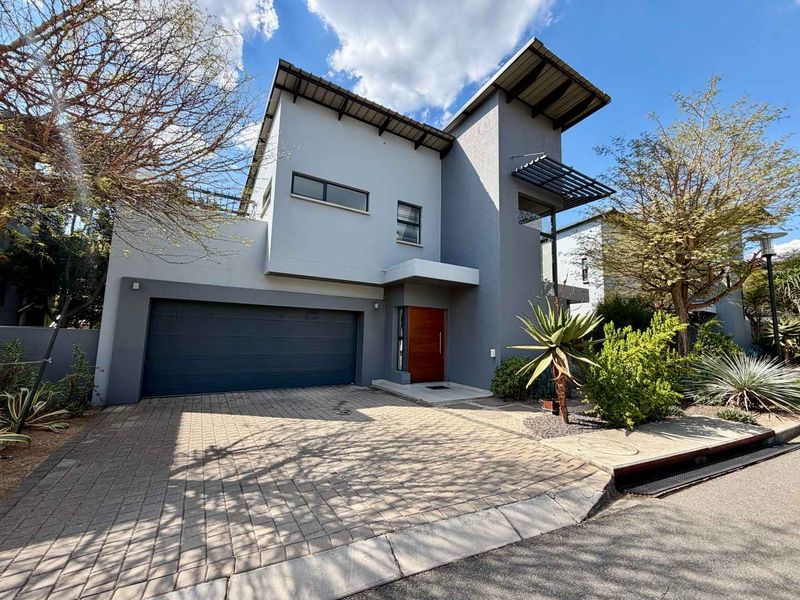 Modern double-story residential home featuring a paved driveway, double garage, and contemporary architectural design with a timber entrance door.