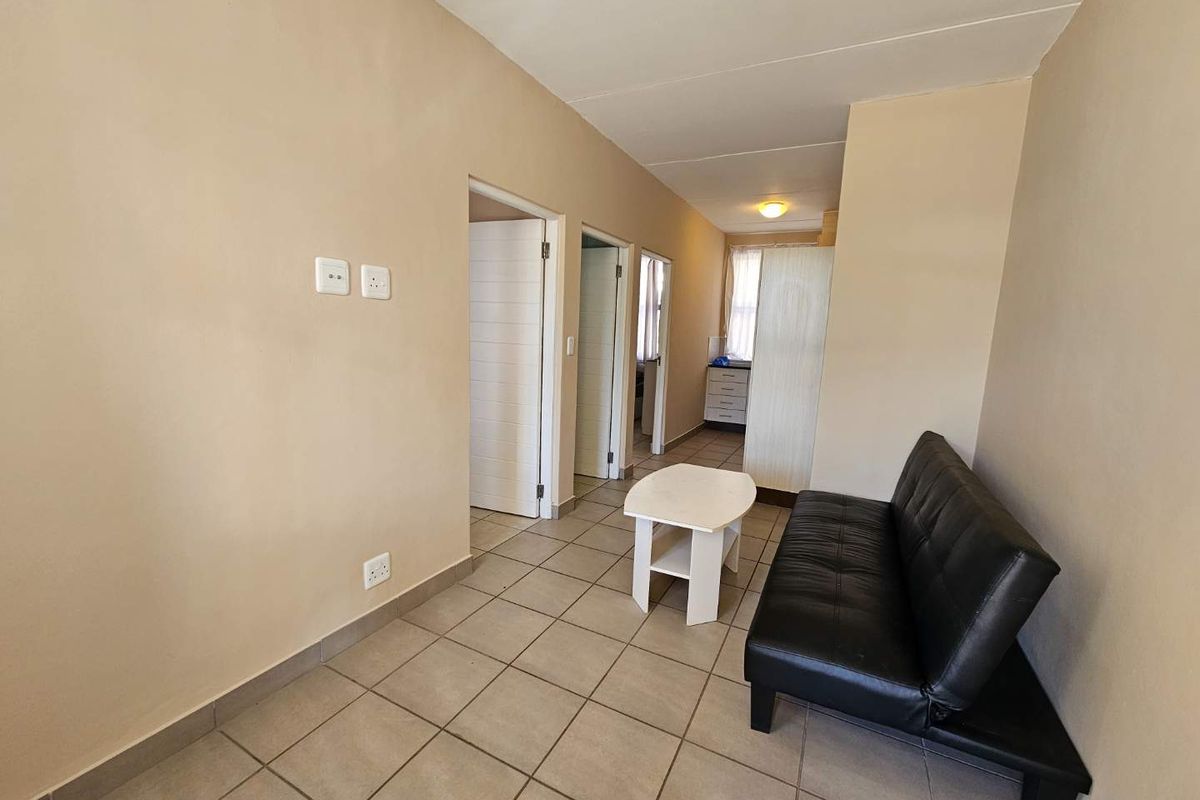 A functional living area featuring neutral wall tones, tiled flooring, and access to adjacent rooms through internal doors.