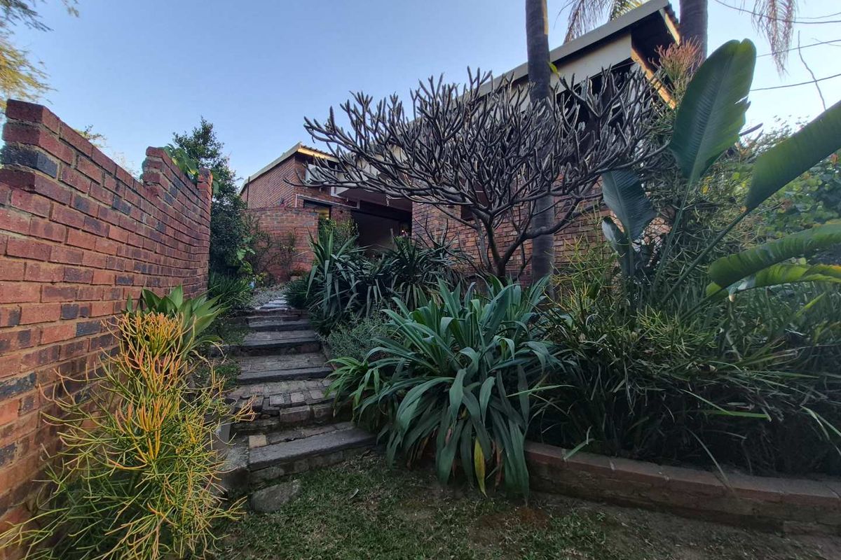 A rear garden view featuring a brick boundary wall and a brick staircase leading towards the property entrance.
