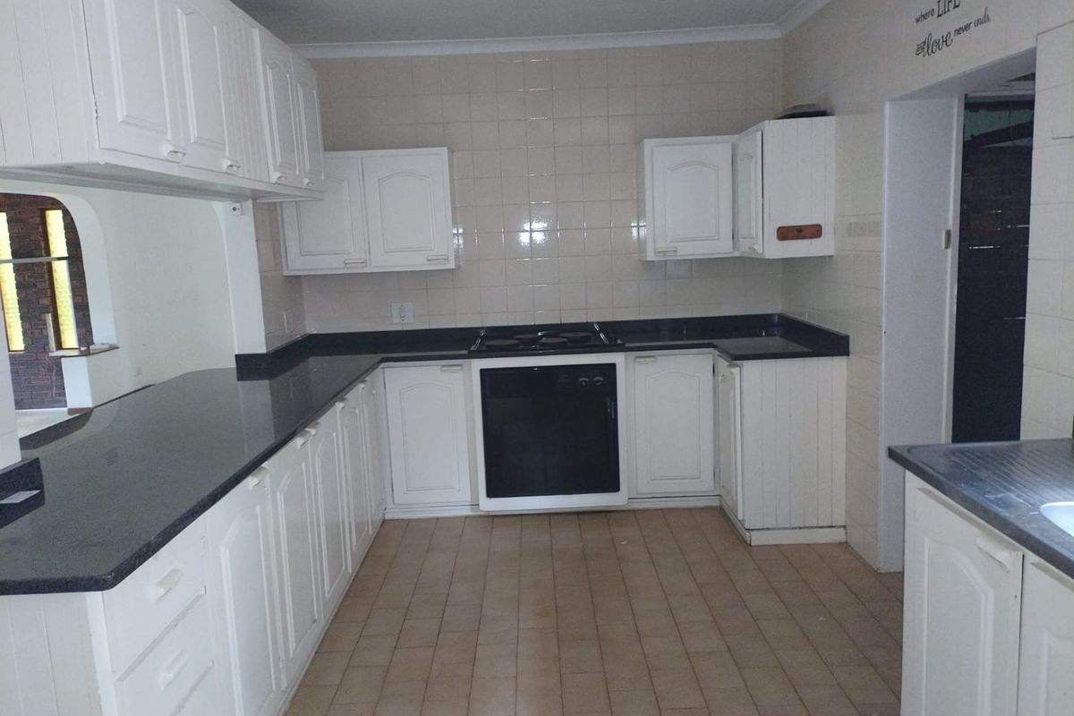 A functional kitchen featuring white built-in cabinetry, dark granite countertops, a built-in oven, and a gas hob with tiled splashbacks.