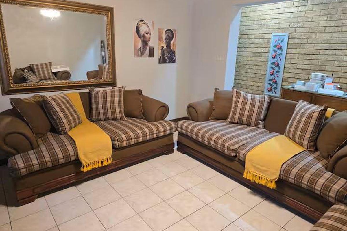 A comfortable living room featuring a textured brick accent wall, tiled flooring, and a wall-mounted air conditioning unit.