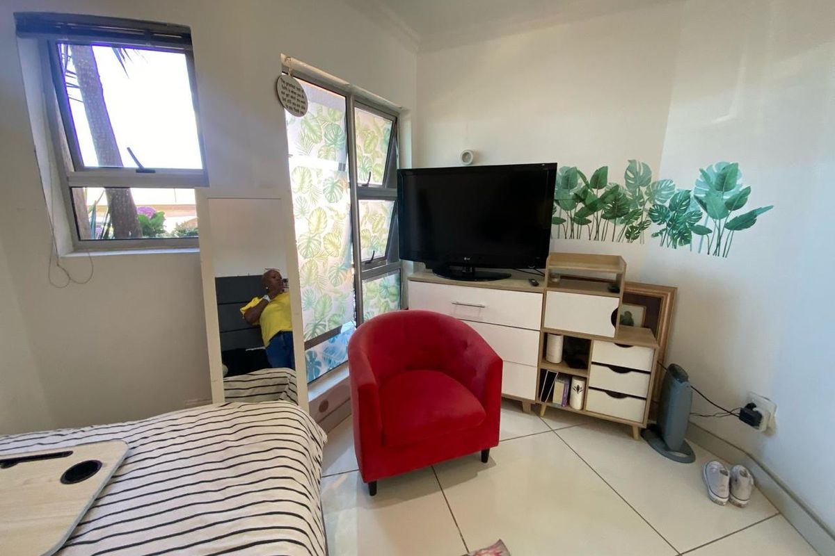A bedroom featuring tiled flooring, large windows with natural light, and neutral wall finishes.