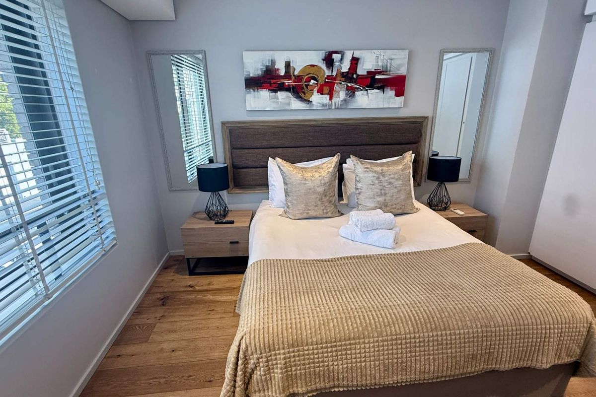 A well-maintained bedroom featuring hardwood flooring, built-in wardrobe storage, and venetian blinds, offering a clean and comfortable living space.