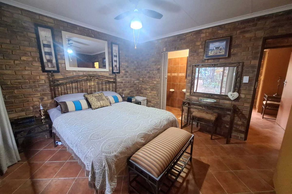 Spacious bedroom featuring exposed brick walls, terracotta floor tiles, and an en-suite bathroom access.