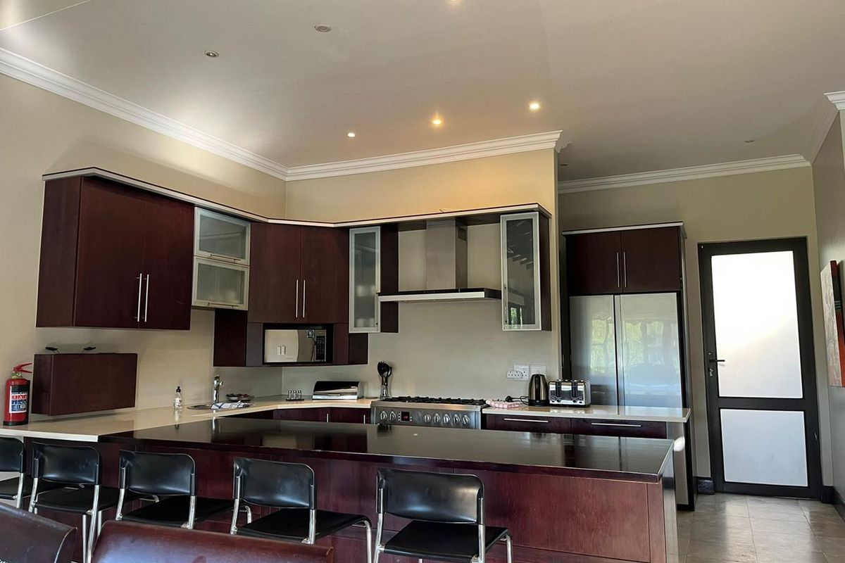 A functional kitchen featuring dark wood cabinetry, a breakfast bar, stainless steel gas stove with extractor fan, and tiled flooring.