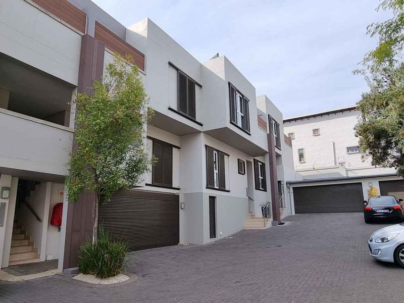 Modern multi-level cluster home exterior featuring paved driveway, integrated garages, and contemporary architectural facade with clean lines.