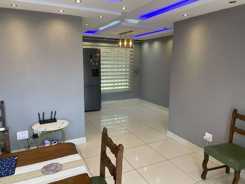 Open plan living area featuring modern recessed ceiling lighting with blue LED accents and polished porcelain floor tiles.