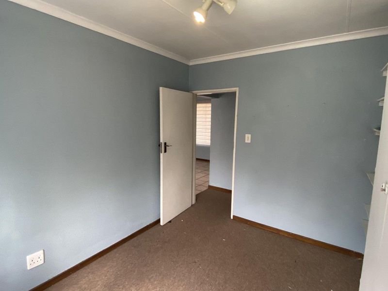 An empty bedroom featuring blue painted walls, carpet flooring, and built-in shelving, offering a blank canvas for personalization.