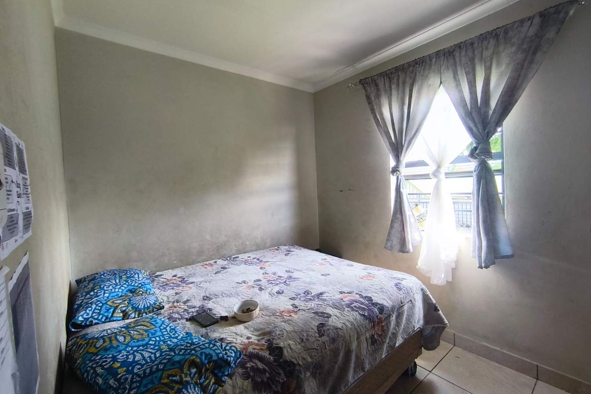 A compact bedroom featuring tiled flooring, a window with curtain fittings, and standard ceiling finishes.