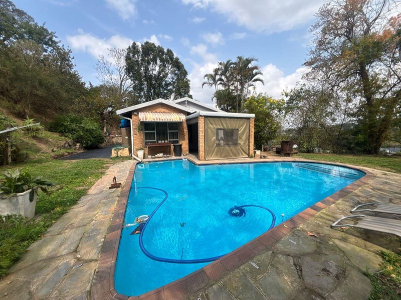 Outdoor pool area featuring a swimming pool with stone paving, brick facade, and a covered patio space.
