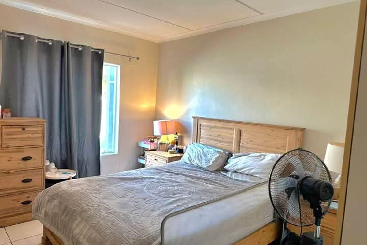 A functional bedroom featuring tiled flooring and coved ceiling details, providing a neutral base for potential interior updates.