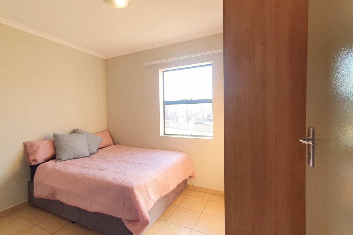 A standard bedroom featuring tiled flooring, neutral wall paint, and a window providing natural light.